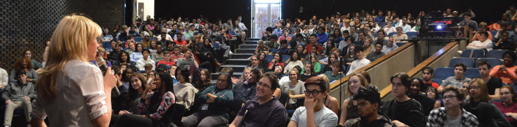 Students in an auditorium listening to Katie Koestner